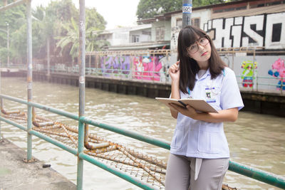 Portrait of female doctor leaning against railing