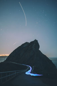 Boardwalk by mountain against sky during sunset