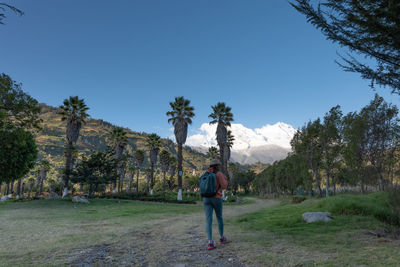 Rear view of woman walking on field against clear sky