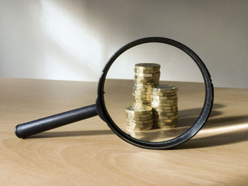 Stack of coins seen from magnifying glass on table