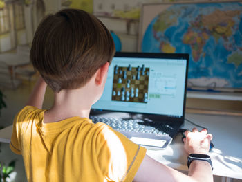 Caucasian boy is taking part in an internet chess tournament by laptop. chess games.