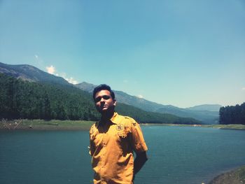 Portrait of man standing by lake against clear sky