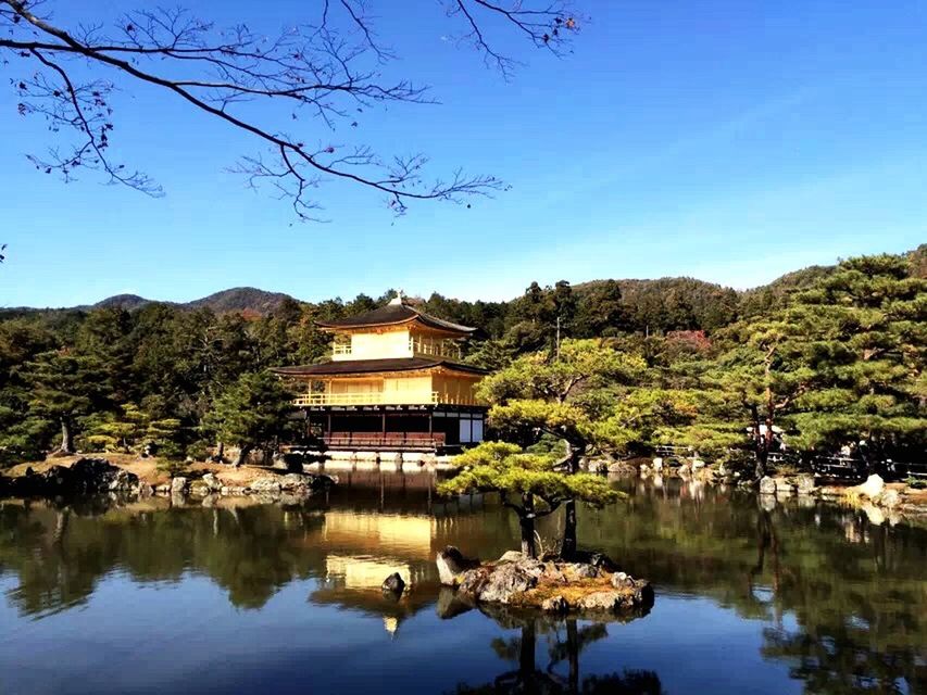 water, architecture, tree, built structure, clear sky, building exterior, reflection, waterfront, lake, house, river, mountain, blue, copy space, standing water, nature, tranquility, day, tranquil scene, sky