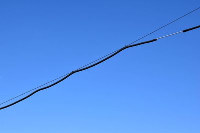 Low angle view of power lines against clear blue sky