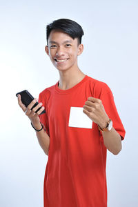 Portrait of smiling man holding smart phone against white background