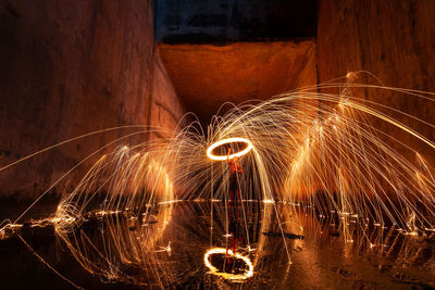 Man spinning wire wool while standing on land at night