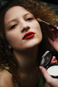 Cropped hands of woman applying make-up on friend face