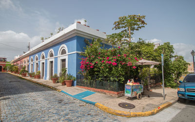 Panoramic street corner view of colorful buildings and flowers and a sidewalk food vendor