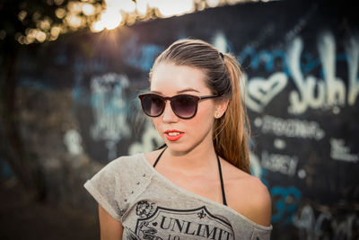 Portrait of young woman wearing sunglasses standing outdoors