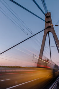 Illuminated light trails on bridge against sky during sunset