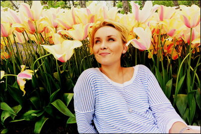 Portrait of smiling young woman standing against plants