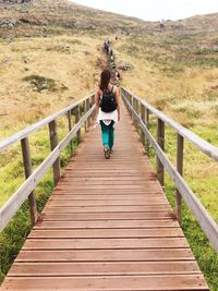 Rear view of woman walking on footbridge