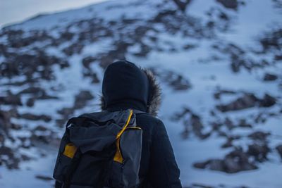 Rear view of man standing on snowcapped mountain