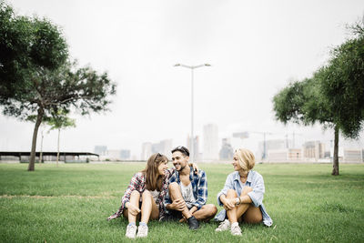 People sitting on field against sky