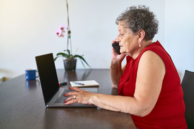 Side view of man using laptop on table at home