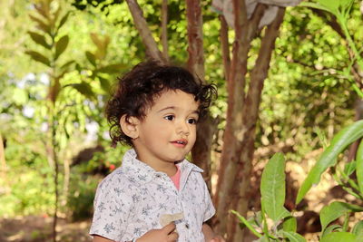 Portrait of cute girl standing against trees