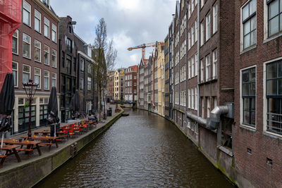 Canal amidst buildings in city against sky