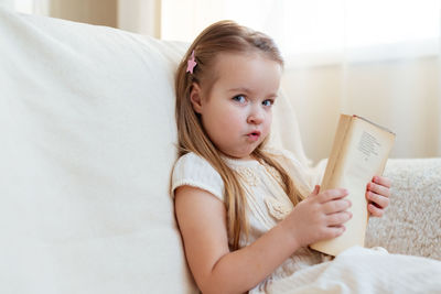 Portrait of cute girl using digital tablet while lying on bed at home