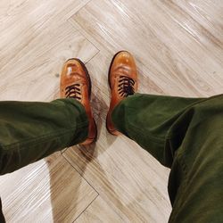 Low section of man wearing shoes on hardwood floor