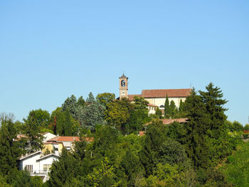 Plants and trees by building against clear blue sky