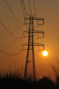 Low angle view of silhouette electricity pylon on field against romantic sky