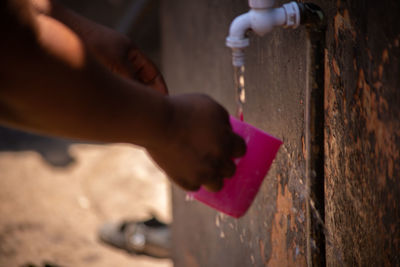 Close-up of person holding hands against wall