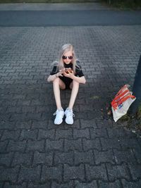 Portrait of woman sitting on footpath