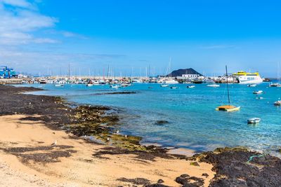 Sailboats moored on beach against blue sky