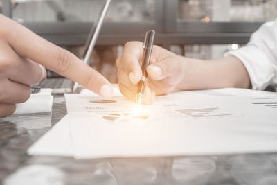 Midsection of person holding paper on table