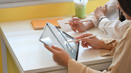 Midsection of businesswomen pointing at digital tablet
