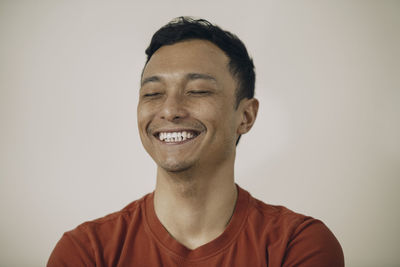 Cheerful man with eyes closed against beige background