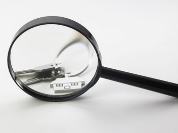 Close-up of house keys seen through magnifying glass on white background