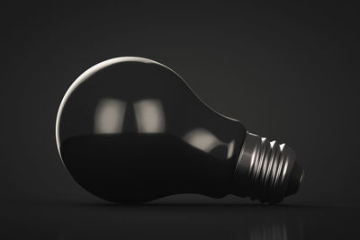 Close-up of light bulb on table against black background