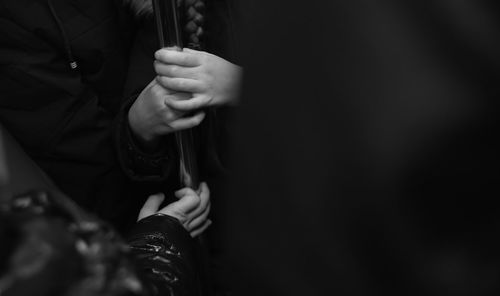 Cropped hands holding pole in subway train