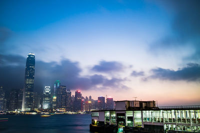 Ship sailing on sea against illuminated city at dusk