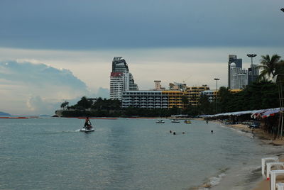 Buildings by sea against sky