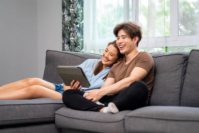 Young woman using laptop while sitting on sofa at home