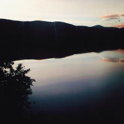 Reflection of silhouette trees in calm lake