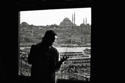 Rear view of silhouette man looking at city buildings