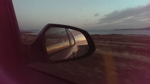 Close-up of side-view mirror at sunset