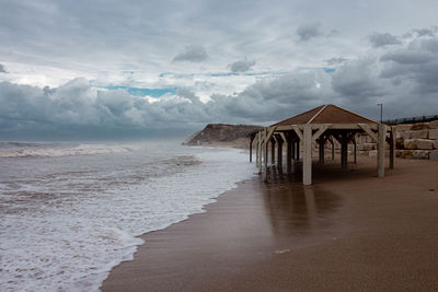 Empty wooden structure on beach against sky