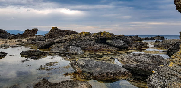 Rocks on sea shore against sky