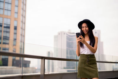 Young woman using mobile phone while standing on camera