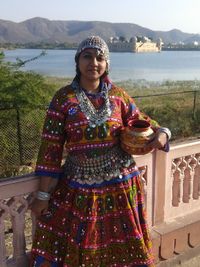Portrait of woman in traditional dress standing against lake