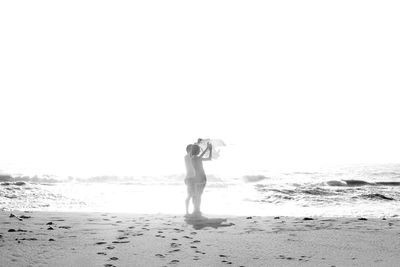 Rear view of man standing on beach against sky