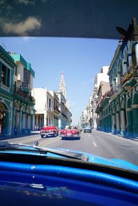 Cars on road in city against blue sky