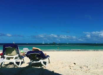 People sitting on beach against blue sky