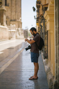 Full length side view of man with digital camera standing on street