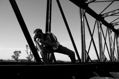 Man photographing while standing on built structure against sky