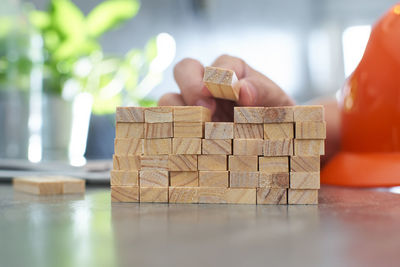 Cropped hand holding wooden jenga block on table